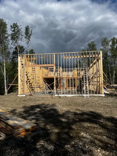 Framed exterior wall against a dramatic Alaska sky