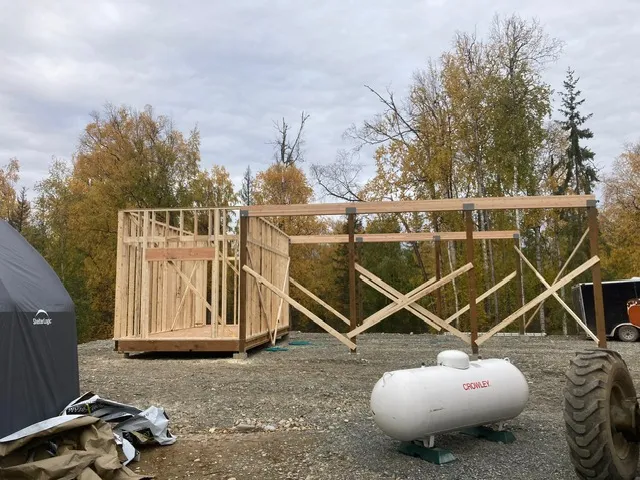 Wood-framed home shell under construction with fall foliage near Wasilla, Alaska