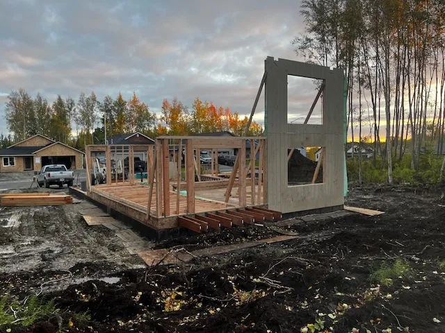 Wood-framed home addition with autumn trees at sunset